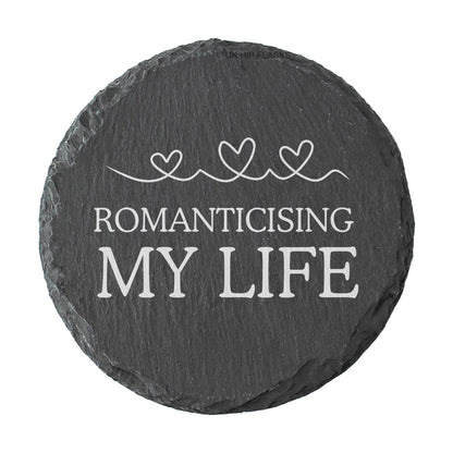Round slate coaster with 'Romanticising My Life' text and heart designs on a white background