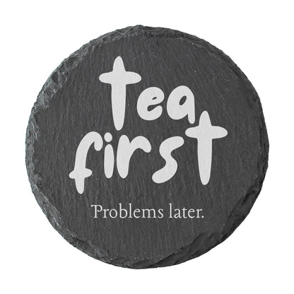 Round slate coaster with the quote "Tea first problems later" in white text.