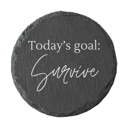 Round slate coaster with 'Today's goal: Survive' text on a white background
