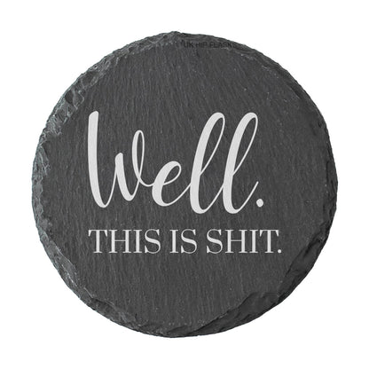 Round slate coaster with text 'Well. This is shit.' on a white background