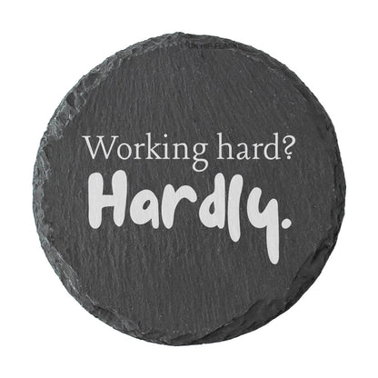 Round slate coaster with motivational quote 'Working hard? Hardly.' on a white background