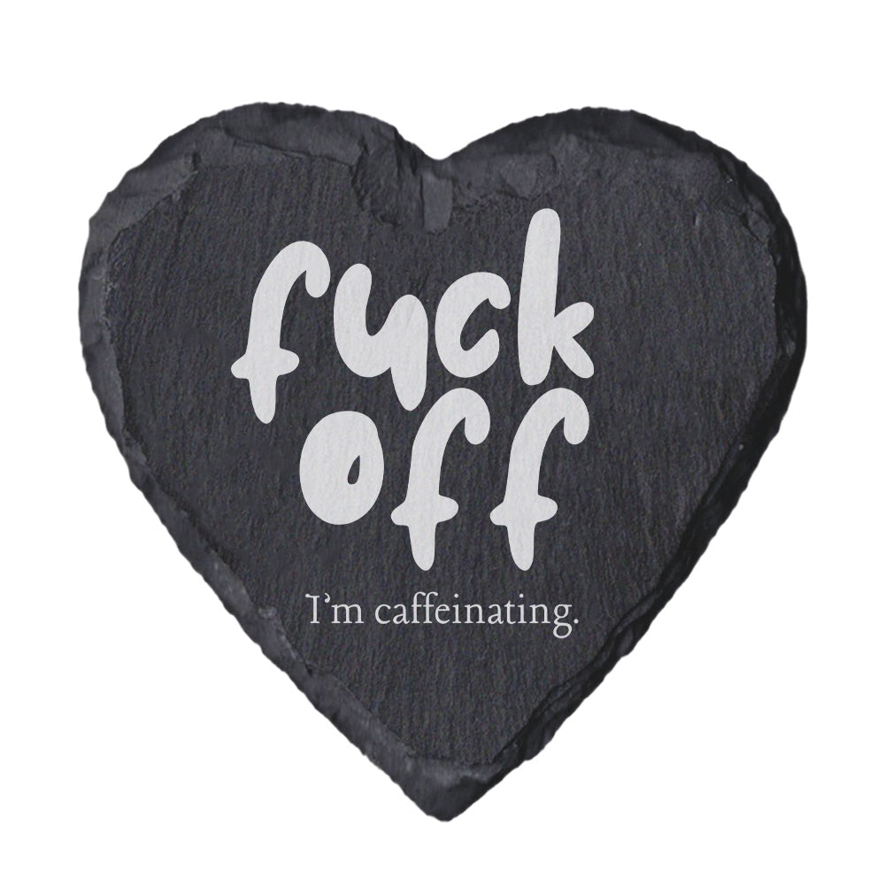 Heart-shaped slate coaster with text 'f*ck off I'm caffeinating' on a white background