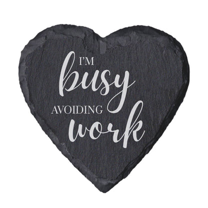 Heart-shaped slate coaster with 'I'm busy avoiding work' text on a white background