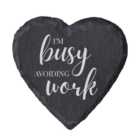 Heart-shaped slate coaster with 'I'm busy avoiding work' text on a white background