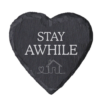 Heart-shaped slate coaster with 'Stay awhile' text and house illustration on a white background