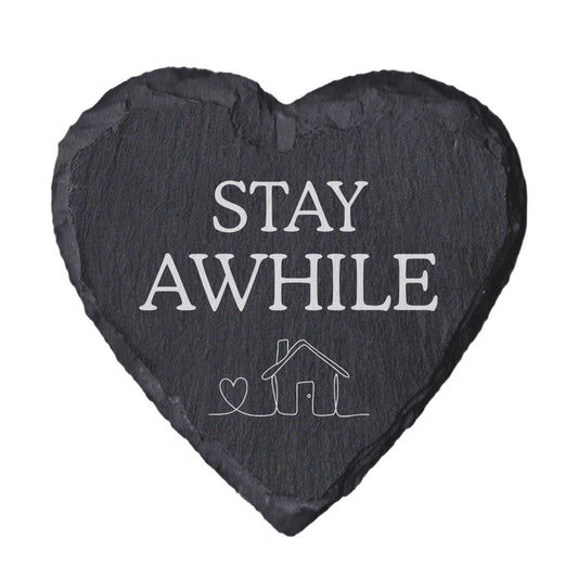 Heart-shaped slate coaster with 'Stay awhile' text and house illustration on a white background