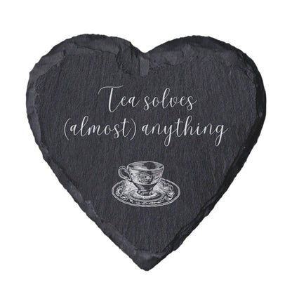 Heart-shaped slate coaster with tea cup illustration and 'Tea solves (almost) anything' text on a white background