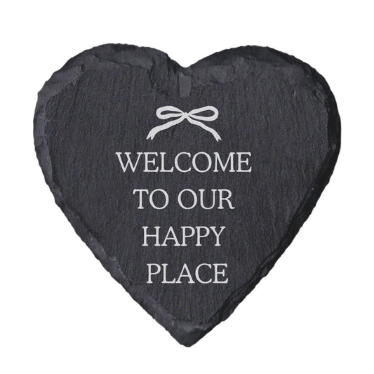 Heart-shaped slate coaster with "welcome to our happy place" quote in white text.