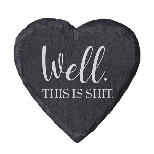 Heart-shaped slate coaster with text 'Well. This is shit.' on a white background
