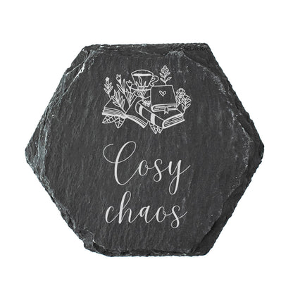 Hexagonal black slate coaster with white text design and text 'Cosy chaos' on a white background