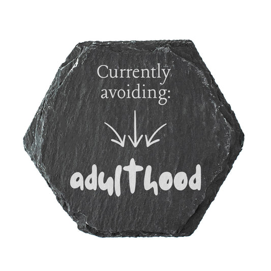 Hexagonal black slate coasters with white text 'Currently avoiding: adulthood'