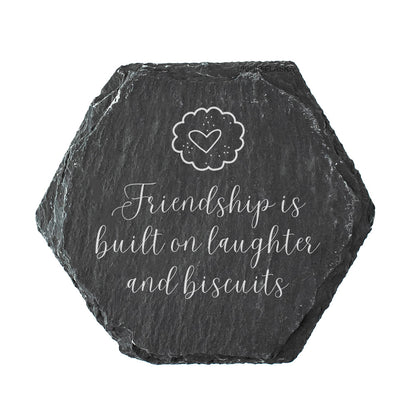 Hexagonal slate coaster with 'Friendship is built on laughter and biscuits' text and a heart design.