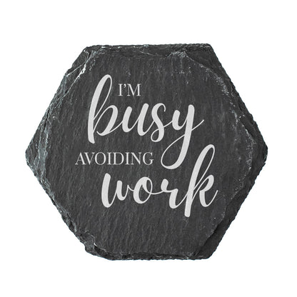 Hexagonal black slate coaster with 'I'm busy avoiding work' text on a white background