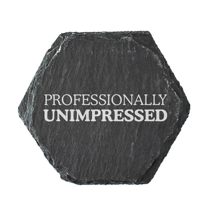 Hexagonal black slate coaster with 'PROFESSIONALLY UNIMPRESSED' text on a white background