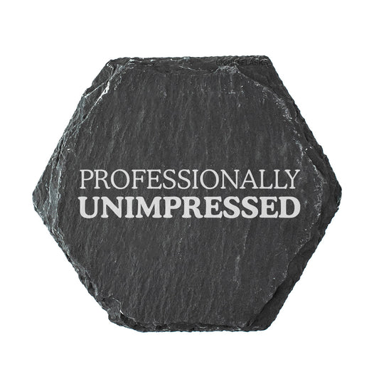 Hexagonal black slate coaster with 'PROFESSIONALLY UNIMPRESSED' text on a white background
