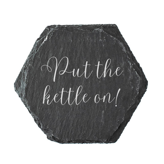 Hexagonal slate coaster with the quote "put the kettle on!" in white text.