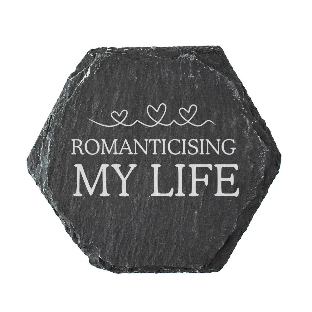 Hexagonal black slate coaster with 'ROMANTICISING MY LIFE' text on a white background