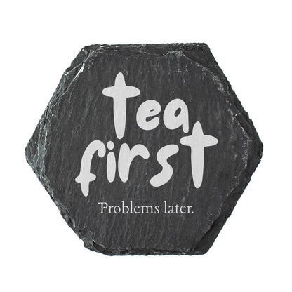 Hexagonal black slate coaster with 'Tea first, Problems later' text on a white background