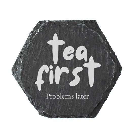 Hexagonal black slate coaster with 'Tea first, Problems later' text on a white background