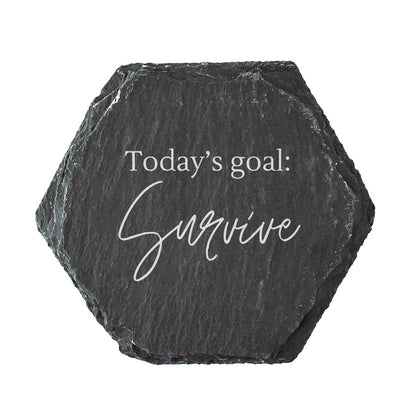 Hexagonal black slate coaster with 'Today's goal: Survive' text on a white background
