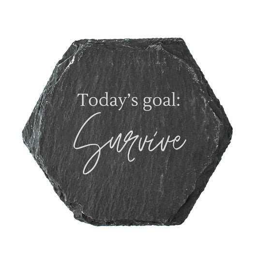 Hexagonal black slate coaster with 'Today's goal: Survive' text on a white background