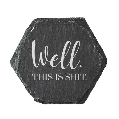 Hexagonal slate coaster with text 'Well. This is shit' on a white background