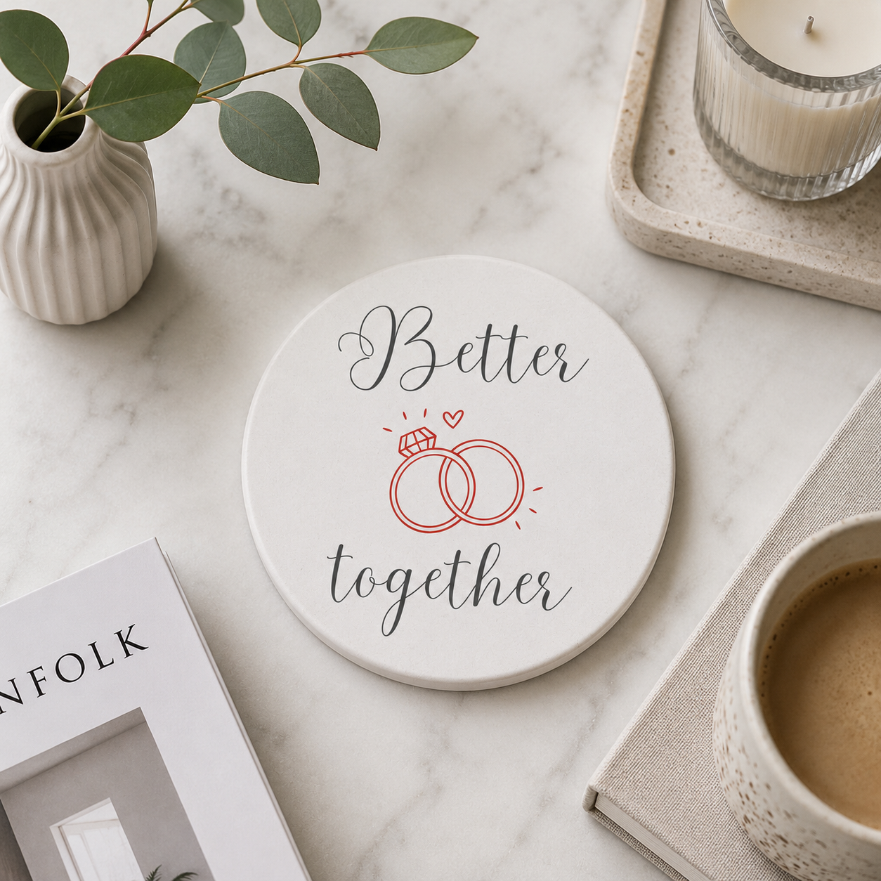 Round ceramic coaster with the quote "Better Together" in black and red text. The coaster is on a marble surface with books and a coffee.