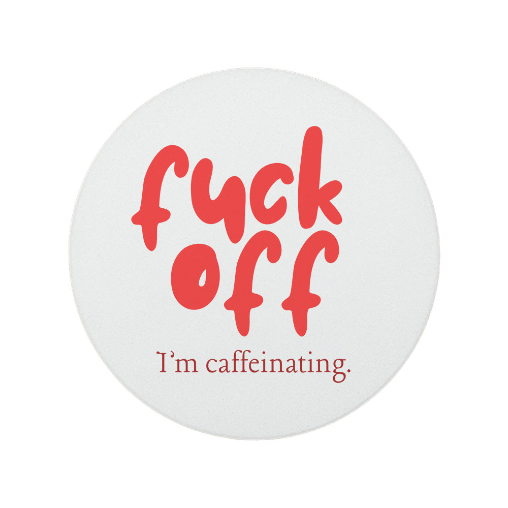 Round ceramic coaster featuring the humorous quote "Fuck off I'm caffeinating" in crisp red lettering.