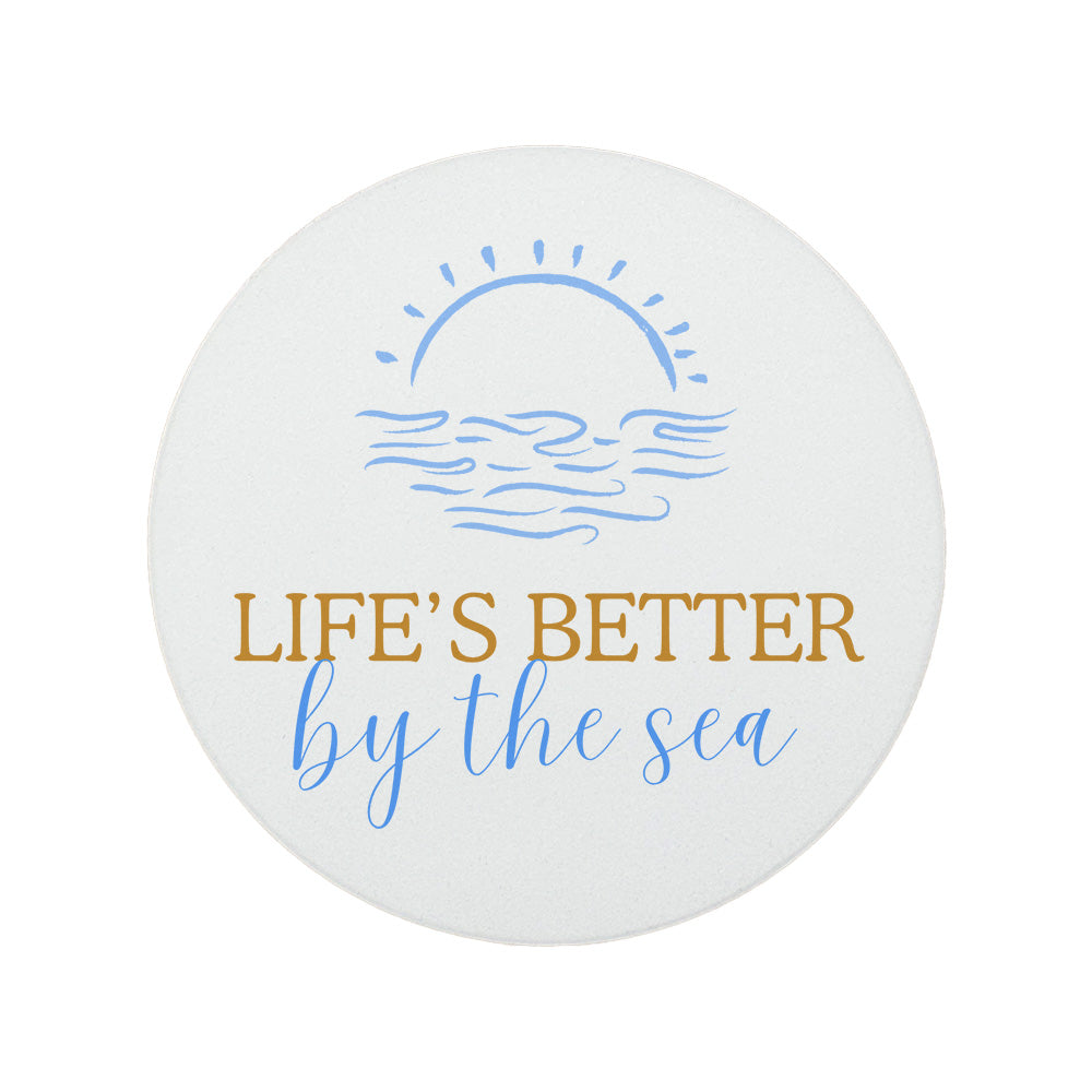 Round ceramic coaster featuring the quote "Life's better by the sea" in blue and gold lettering and a sun and sea illustration. 