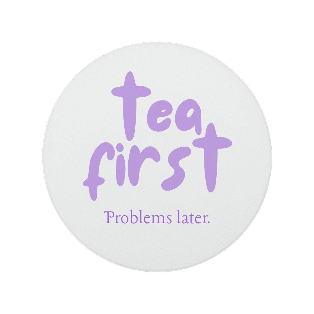 Round ceramic coaster featuring the humorous sarcastic quote "Tea first, problems later." in crisp purple lettering. 
