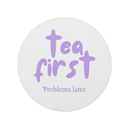 Round ceramic coaster featuring the humorous sarcastic quote "Tea first, problems later." in crisp purple lettering. 
