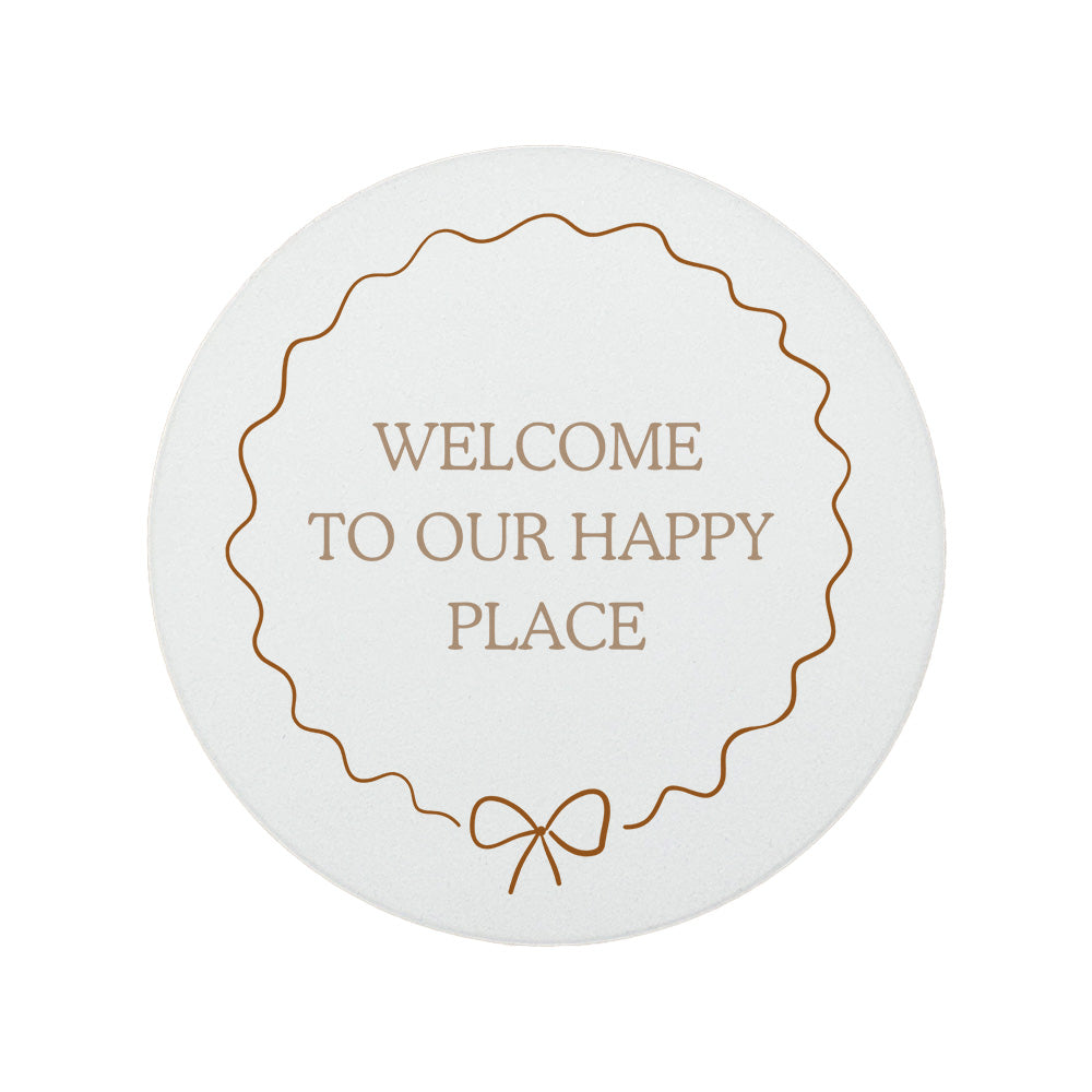 Round ceramic coaster featuring the quote "Welcome to our happy place" in neutral toned lettering with a cute bow border.