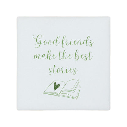 Square ceramic coaster featuring the friendship quote "Good friends make the best stories" in crisp green lettering with a book illustration underneath.