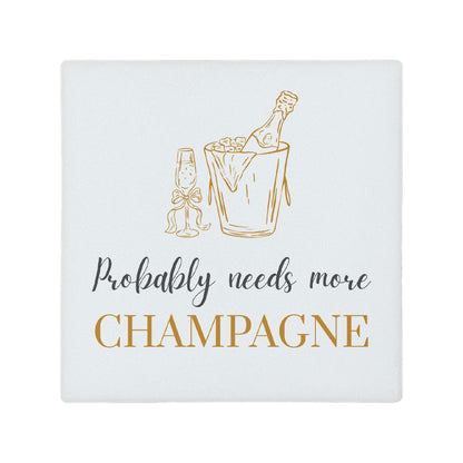 Square ceramic coaster featuring the funny quote "Probably needs more champagne" in crisp grey and gold lettering with a champagne bottle illustration. 