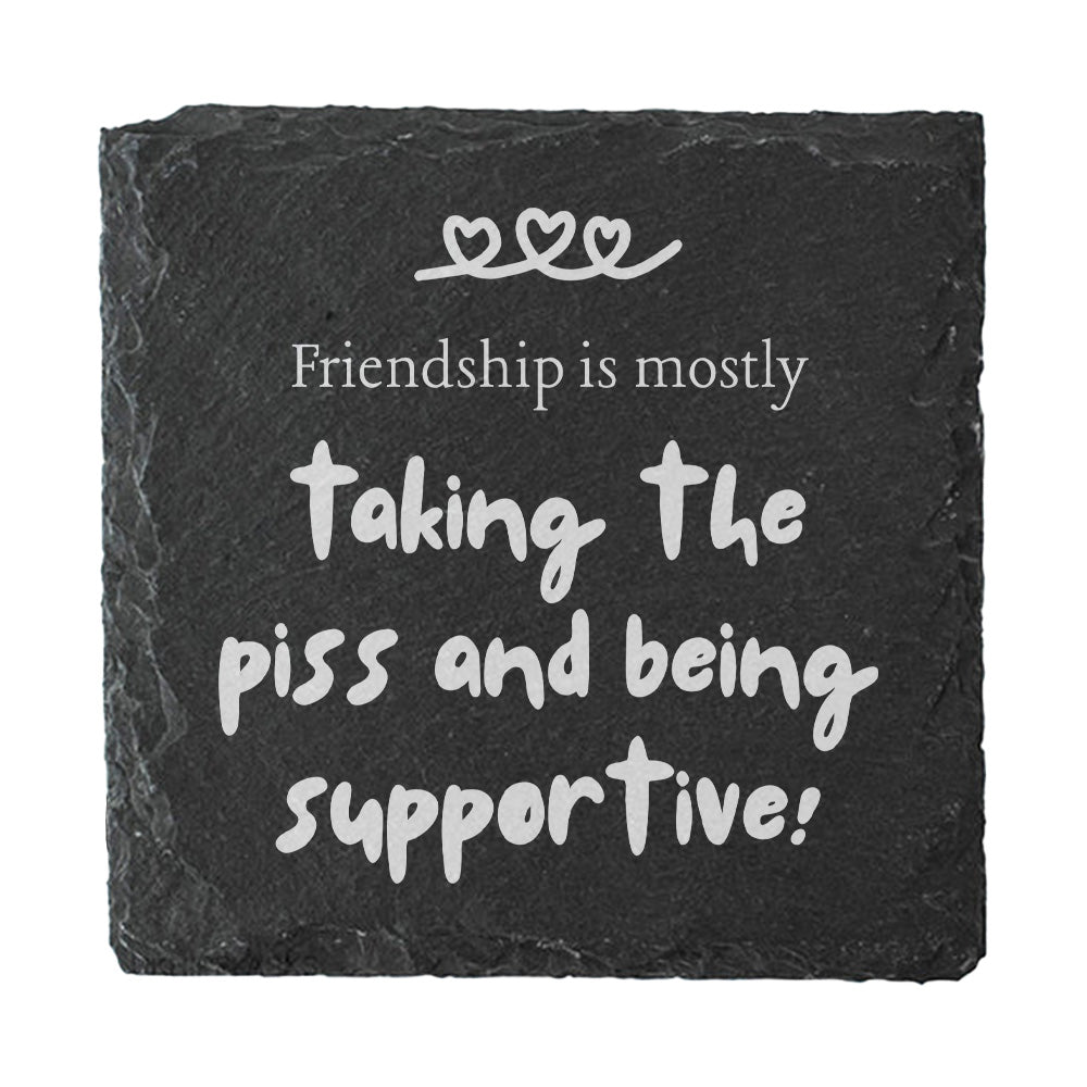 Black slate coaster with white text 'Friendship is mostly taking the piss and being supportive!'
