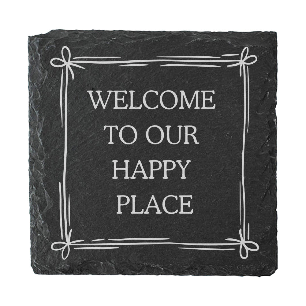 A slate coaster with the quote "Welcome to our happy place" in white text.