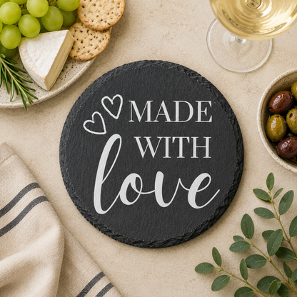 Round slate coaster with 'Made with Love' text on a table with food and wine.
