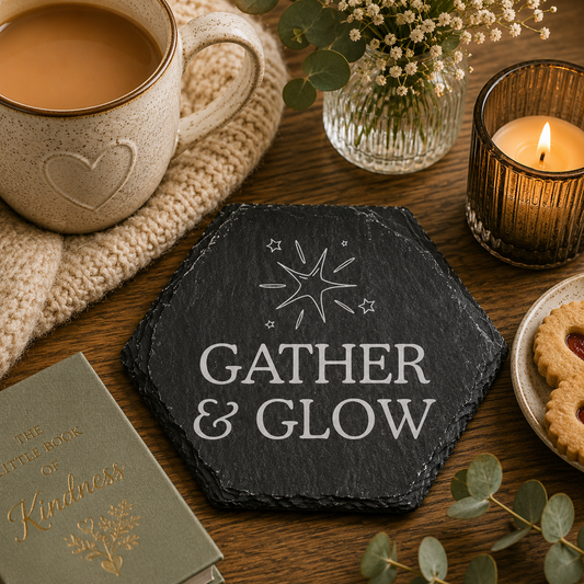 Hexagonal slate coaster with 'gather and glow' text on a wooden surface with plants, mug of tea and candles.