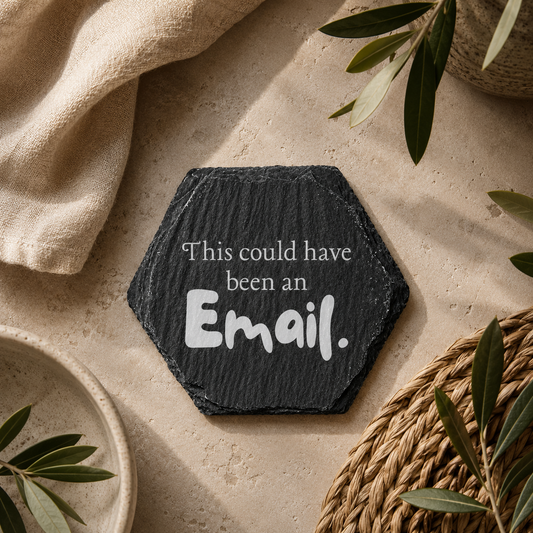 Hexagonal slate coaster with 'this could have been an email' text on a wooden surface with plants.