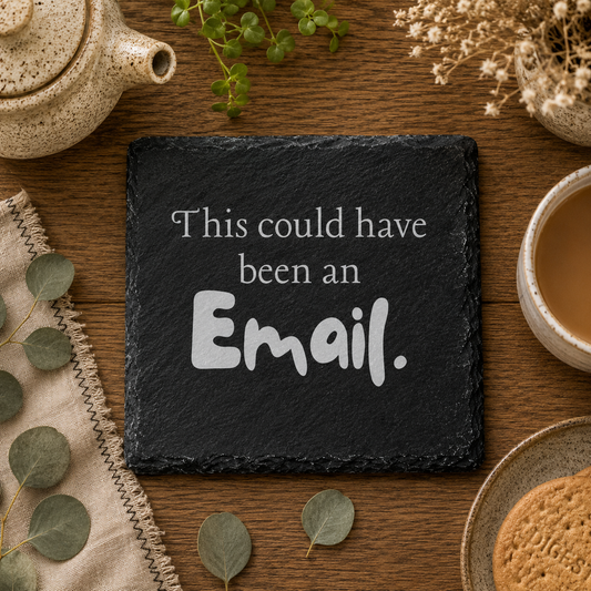 Slate coaster with 'This could have been an Email.' text on a wooden table with tea and cookies.