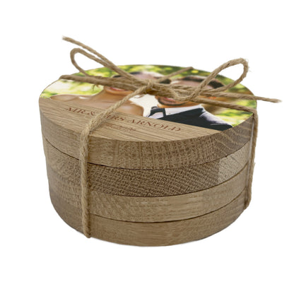 Stack of wooden coasters with a personalised wedding photo and text tied with twine on a white background